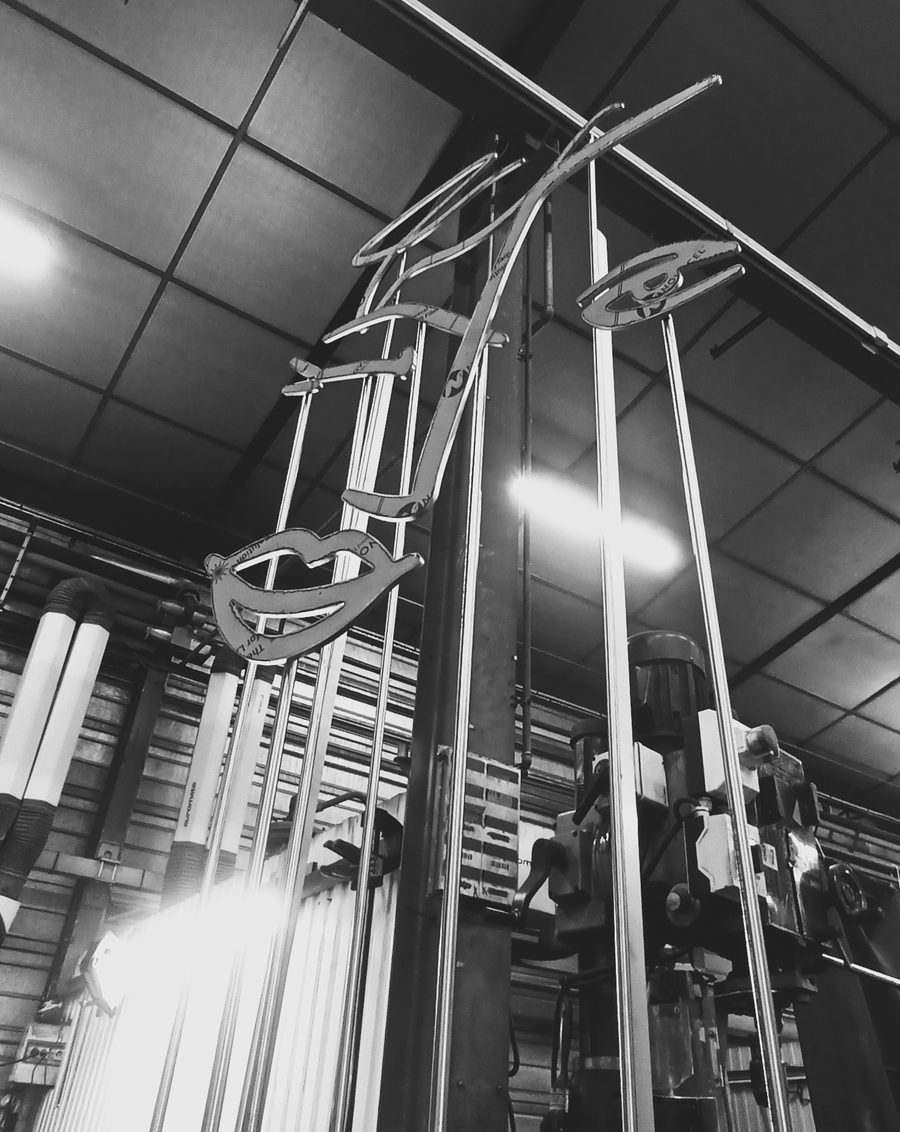 Profil de visage découpé dans l'inox, suspendu dans l'atelier