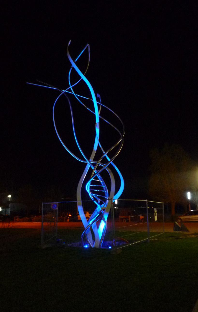 Double hélice d'ADN en inox, illuminée de bleu dans la nuit