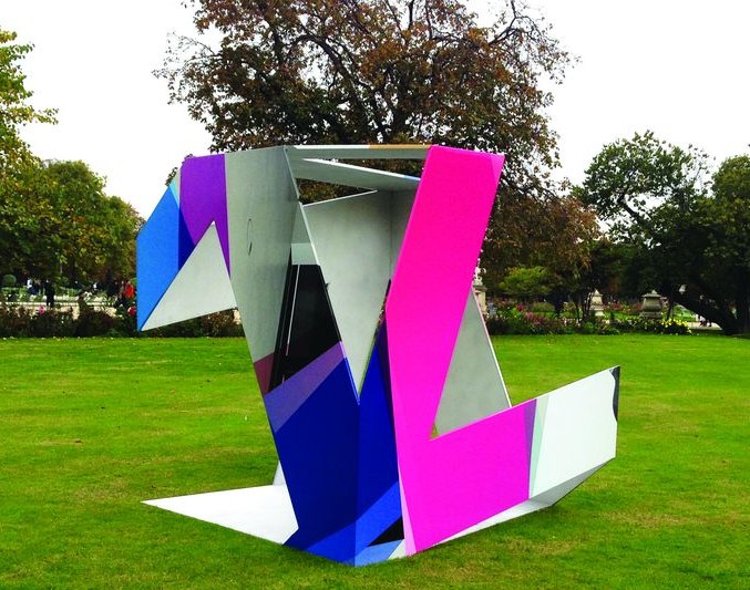 Sculpture en tôles pliées roses et bleues posée sur une pelouse