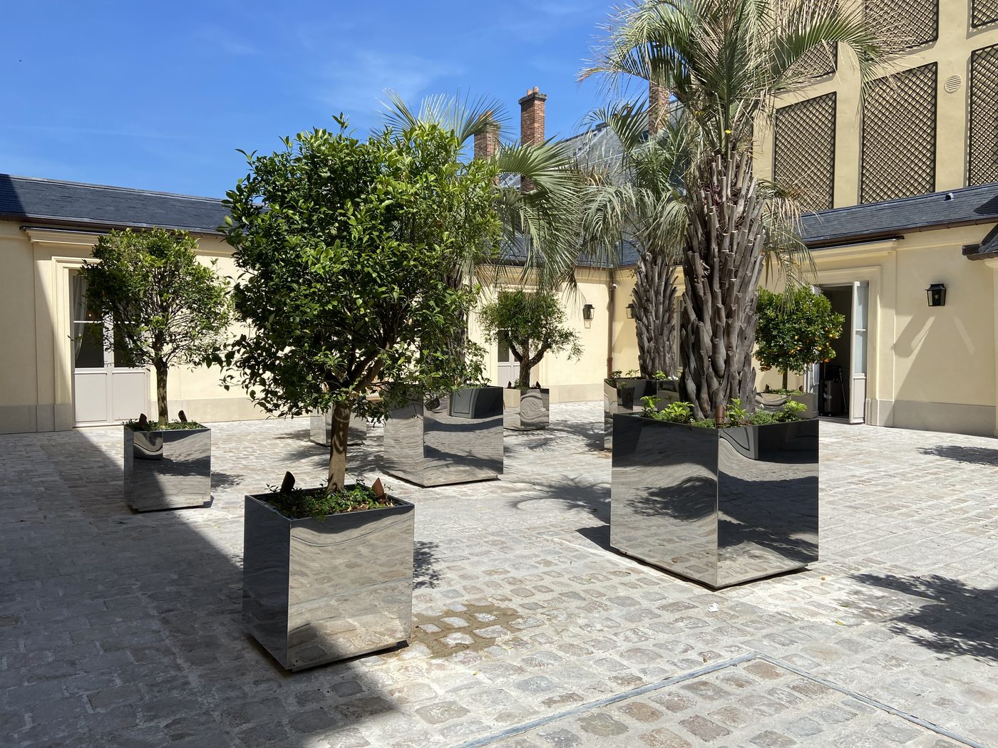 Bacs d'orangerie en inox poli miroir dans une cour de Versailles